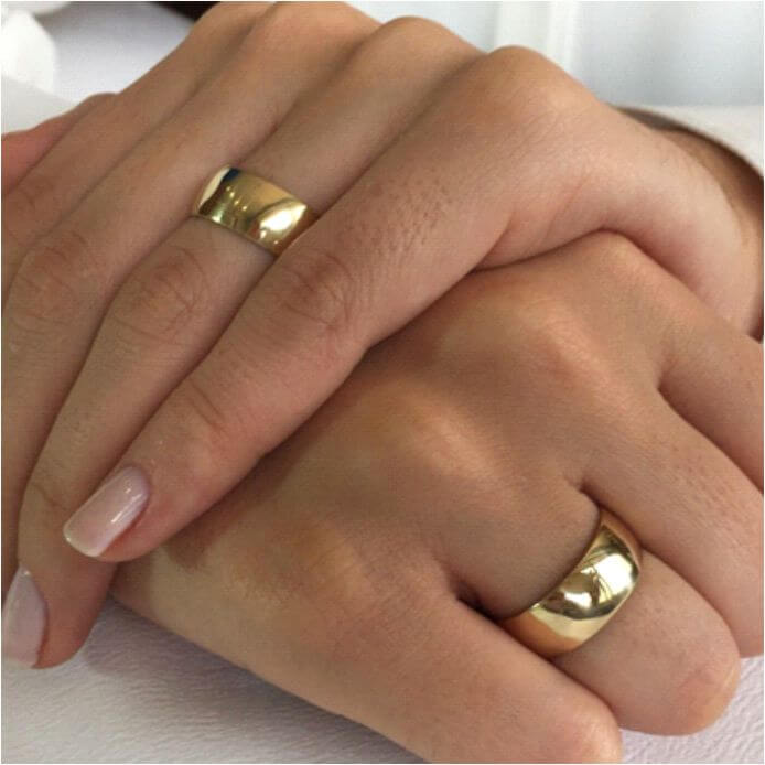Imagem - Casal de mãos unidas, exibindo as alianças de casamento simbolizando amor e compromisso.